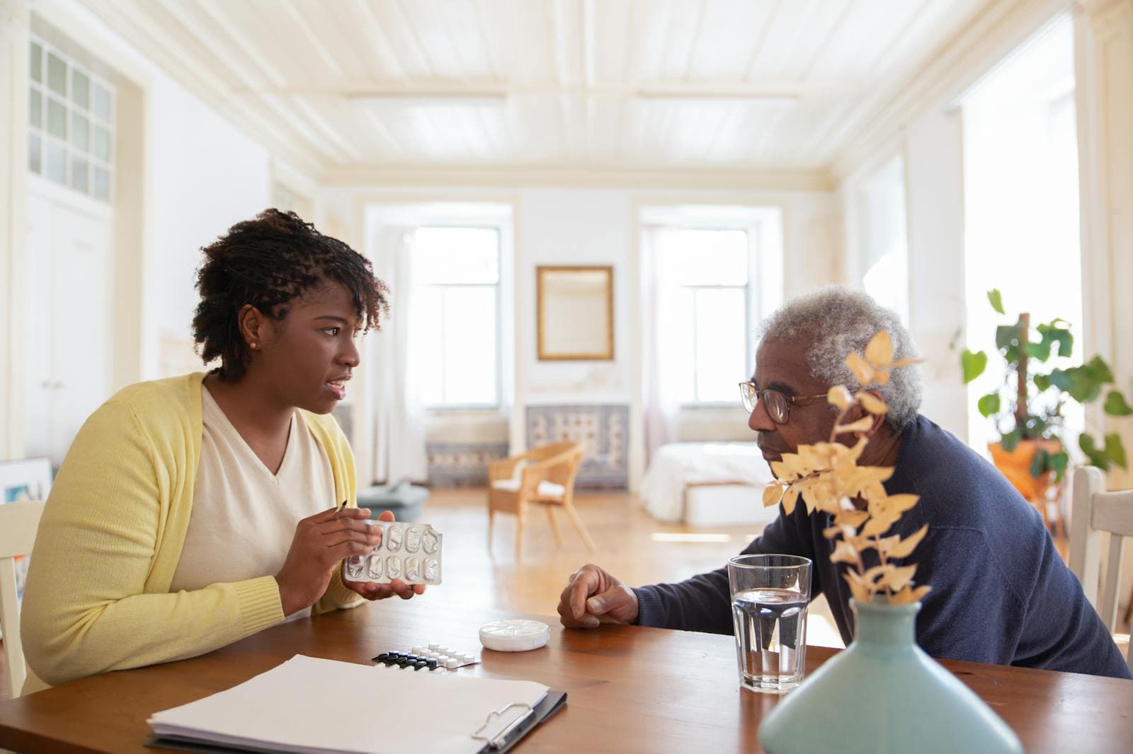 A caregiver discussing support and medication with an older adult at home
